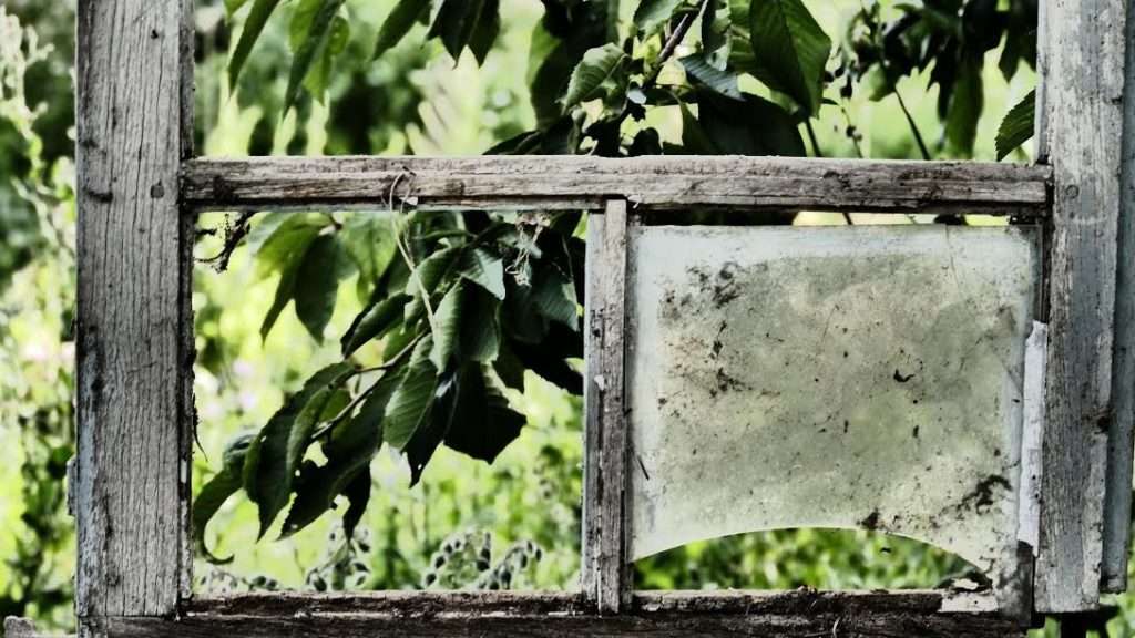 Photo of wooden window frame with broken glass.
