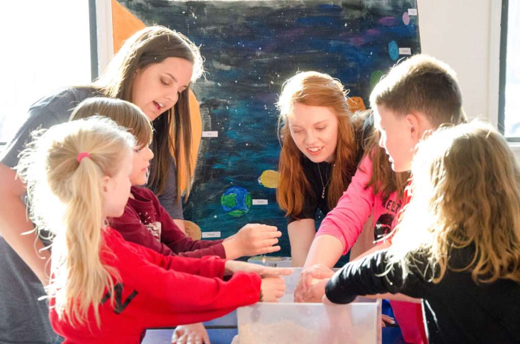 Shorter education majors let students at Pepperell Primary School play with Moon Sand while teaching about the solar system.